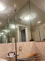 Chrome towel stand with soap dish and brass accents reflected in bathroom mirror