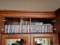 Full cabinet shelf showing approximately 70 DVD cases lined side by side
