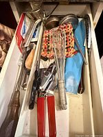 Drawer showing assorted utensils including whisks, ladle, can opener, tongs