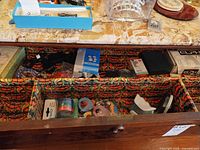 Open drawer showing camera, tapes, label maker, cords and chess set