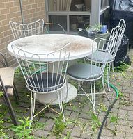 resin patio table with four metal chairs positioned around it