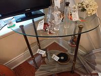 Full view of two-tier glass and brass side table with TV and decor on top