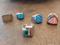 All five sterling silver rings laid out showing designs and stones