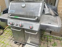 Front view of Weber Genesis grill showing burners, doors, and side shelf