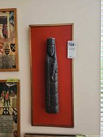 Front view of framed wooden carving on orange backing