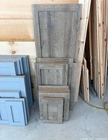 Stack of brown shaker cabinet doors in multiple sizes leaning against wall