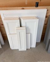 Stack of white shaker cabinet doors of assorted sizes