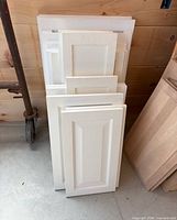 Stack of white cabinet doors leaning against wall