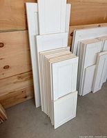 Front view of stacked white cabinet doors of varying heights and widths