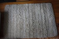 Top view of a rectangular curly, high pile area rug showing natural off-white colors and texture.