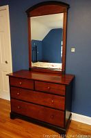 Full view of dresser with mirror attached above it, showing the cherry wood finish and overall design.