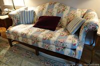 Ethan Allen floral loveseat with two throw pillows and armrest covers in a living room setting.