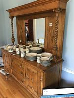 Full front side view of walnut buffet with various dishes on top.