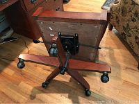 Underside view of cherry wood five-star swivel base with caster wheels and tilt mechanism