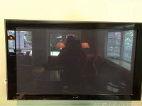 Front view of black framed Pioneer Elite plasma flatscreen TV with a dark reflective screen and visible room reflection.