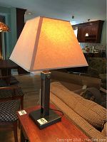 Single Crate And Barrel table lamp with beige square fabric shade and black rectangular base on wooden table.