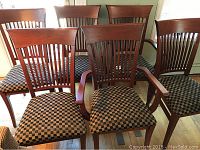 Front view of two host chairs with arms in front and four side chairs in the back showing cherry wood frames and checkered upholstery.