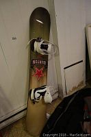Full view of the golden colored Burton King 158 snowboard with mounted white bindings, showing Burton logo and red star decal.