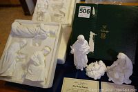 Photo of several white bone china nativity figures arranged near original green Lenox box and certificate of authenticity.