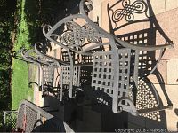 Three chairs lined up on tiled patio showing side profile and decorative back motif