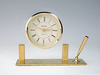 Front view showing brass Bulova clock in acrylic arch on brass base with pen holder