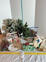 Overall lot with three trees, ornament box, plate, linens, greenery bag