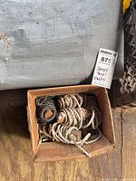 Box of coiled polypropylene ropes beneath folded gray tarp edge