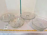 Overview of four clear pressed and cut glass serving pieces