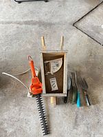 All items laid out: hedge trimmer, wheelbarrow planter, three hand tools