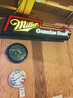 All three items mounted on wall: Miller sign illuminated, Corona clock, Springfield thermometer