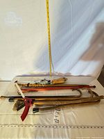 Stack of five canes and two reachers laid flat with measuring tape for scale