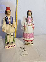 Front view of both Metaxa ceramic decanter figurines