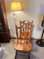 Two oak dining chairs in front of painted floor lamp with shade