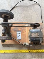 Top view of bench grinder showing motor, belt, wheels, and wood base
