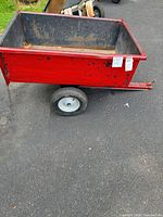 Side view of red garden trailer cart on pavement
