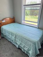 Complete twin bed setup with comforter over mattress and headboard visible