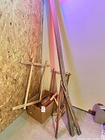 Group of wooden stretcher rails leaning against wall with box of smaller pieces