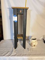 Full view of wood plant stand and ceramic vase with tape measure for scale