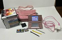 Full bundle showing console, charger, carry bag, styluses, 11 game cases/cartridges