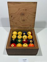 Open wood box showing full set of balls