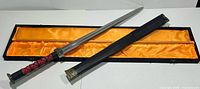 Sword, sheath and open presentation box showing orange satin lining