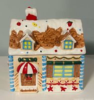 Front view of ceramic gingerbread house cookie jar with roof lid on