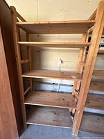 Full view of wooden shelving unit showing five shelves and side peg holes