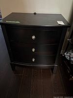Full view of black three-drawer chest with metal knobs