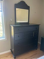Full view of black dresser with attached mirror and drawers closed