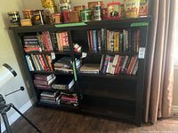Front view of black bookshelf filled with books and cans showing overall structure and dimensions label
