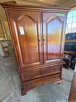 full view of brown wooden armoire showing two doors and two lower drawers