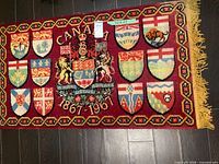 Full view of commemorative rug showing coat of arms, shields, fringe