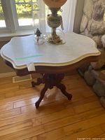 Full view of marble-top pedestal table next to window