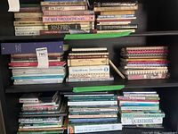 Three shelves filled with assorted cookbooks and gardening guides